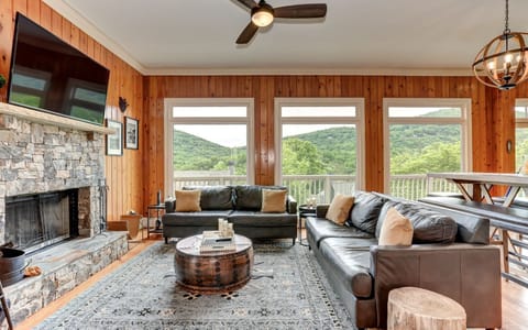 Leather sofas, stone fireplace, mountain view - luxury lodge living.