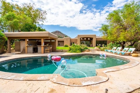 Relax by the private pool with a shaded outdoor bar area in this desert-style home.