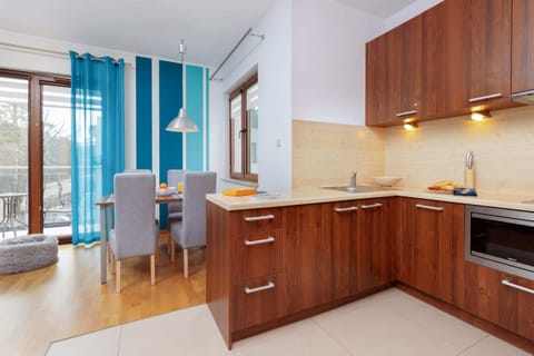 A modern kitchenette with wooden cabinets, a stovetop, built-in microwave, and a bright countertop for meal prep.