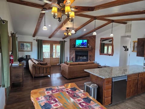 Living room with vaulted beamed ceiling, log-frame windows, and doors out to the