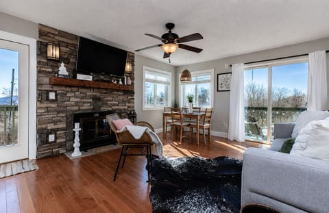 Cozy living room with wood burning fireplace and door leading to balcony. Open-concept living space—perfect for relaxing together