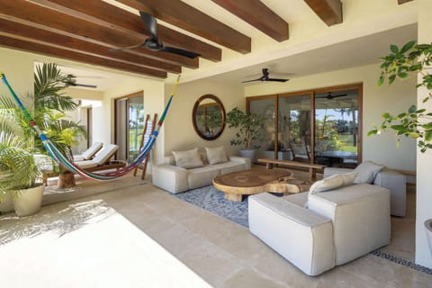 Spacious covered terrace featuring comfortable lounge seating, artisan hammocks, and warm wood-beamed ceilings — an inviting setting to unwind while embracing the surrounding tropical landscape