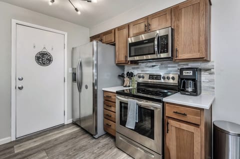- Stainless steel appliances including a French door fridge and electric range
- Modern backsplash and wood cabinetry create a warm functional atmosphere
- Fully equipped with coffee maker knives and all your cooking essentials