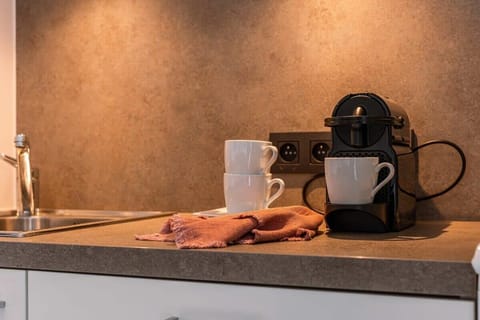 Cozy kitchen corner with a coffee machine, mugs, and modern lighting—perfect for your morning brew. Clean, stylish, and fully equipped for a comfortable stay.