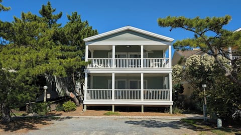 105 Cedarwood Street Front Exterior View of Two-Story Coastal Ho - A front-facing view of the property showcasing the two-story structure with prominent white-railed porches on both levels and a paved driveway.