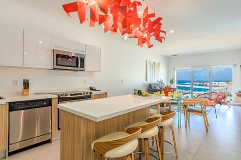 Bright, modern kitchen with a stunning sea view where you can cook breakfast, share meals at the island, and gaze out over blue waters.