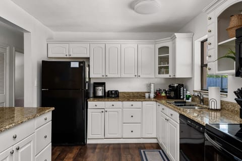 This fully equipped kitchen with sleek white cabinets and state-of-the-art black appliances is a chef's dream come true.