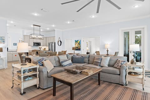 Sink into the plush sectional sofa where coastal elegance meets comfort in this open-concept living space with vaulted ceilings and natural light.