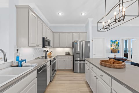 Cook memorable meals in your spacious, fully-equipped kitchen featuring modern appliances, elegant white cabinetry, and sleek countertops perfect for gathering.