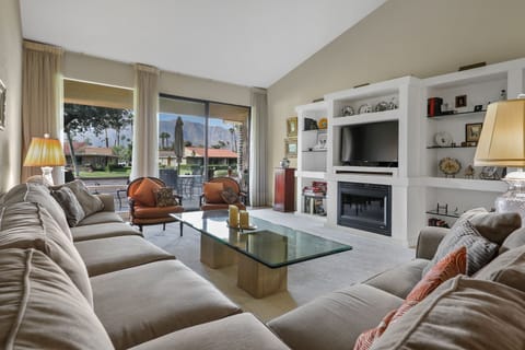Living room w/ wall of glass offering views of patio, mountains and golf course.
