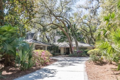 A long, sun-drenched driveway leads to a charming single-story home.