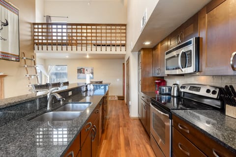 Full size kitchen with granite countertops, stainless steel appliances, hardwood floors and breakfast bar with seating for four.
