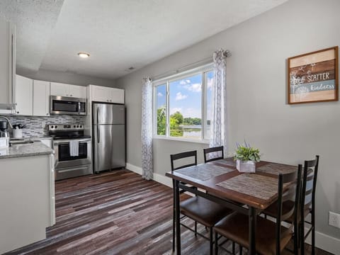 Kitchen and dining area with stainless appliances - Window views overlooking sparkling lake scenery - Perfect setup for shared meals and gatherings