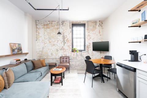 An open-concept living area designed for both relaxation and productivity, complete with a dining table/workspace, high-speed Wi-Fi, and original Cream City brick