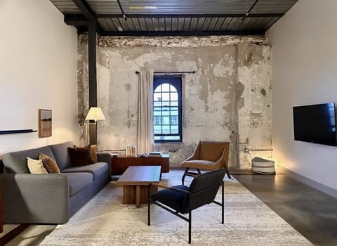 An open-concept living area designed for both relaxation and productivity, complete with a dedicated workspace, high-speed Wi-Fi, and original Cream City brick