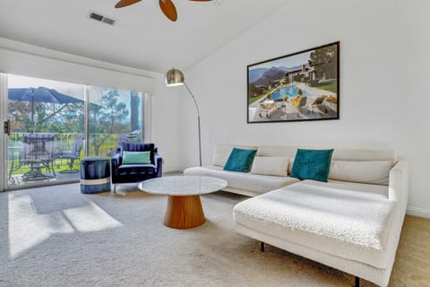 Living room with private balcony and view of golf course and mountains.