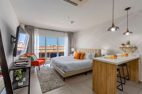 Your bright, modern studio awaits with a cozy bed, pops of color, and a sleek kitchenette perfect for morning coffee before stepping onto your private balcony.