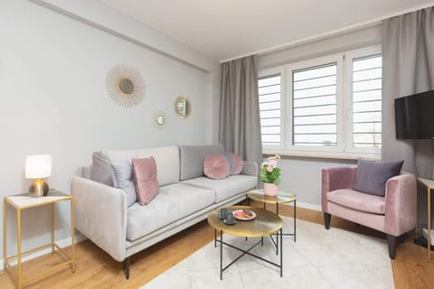Cozy living room with a sofa, coffee table, and large window providing natural light.
