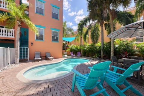Multi-story home exterior with private pool, lounge chairs, and tropical landscaping