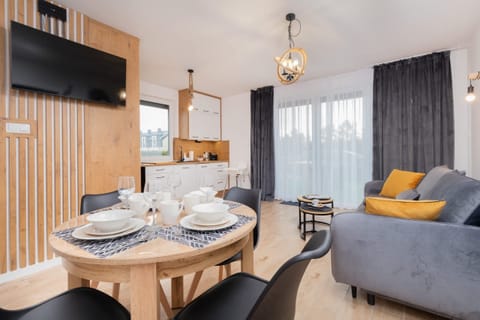 A dining space with a wooden table and four black chairs, set with plates, glasses, and napkins for a meal.