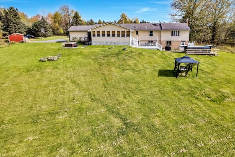View of house from yard with hot tub, swim spa, gazebo, firepit.