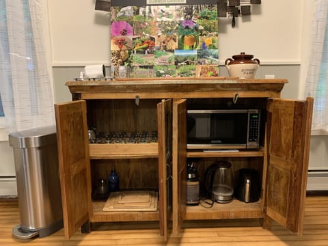 Kitchen cupboard stocked with spice collection, microwave, coffeemaker & teapot
