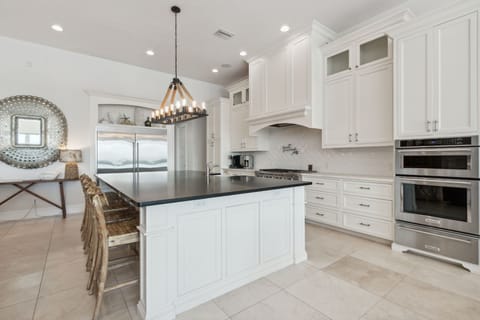 Fully Equipped Kitchen with Oversized Island, Stainless Steel Appliances, Farm Sink, Gas Stove, and Bar Stool Seating