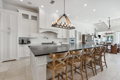 Fully Equipped Luxury Kitchen with Magnificent Oversized Island, Stainless Steel Appliances, Farm Sink, Gas Stove, and Bar Stool Seating