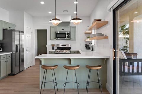 Newly renovated kitchen space with white quartz countertops + floating shelves