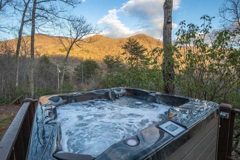 Private hot tub on the deck overlooking the golden-hued Great Smoky Mountains at sunset.