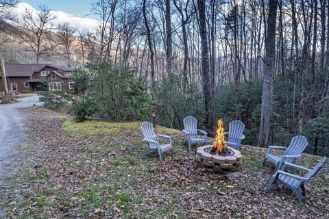 Outdoor fire pit with Adirondack chairs tucked into a wooded setting at Deer Creek Lodge in Bryson City.