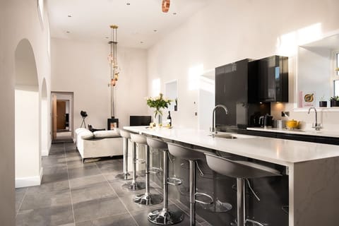 The Steading at West Lyham - spacious double-height kitchen with island and sitting room with corner sofa and Morsø stove