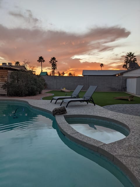 Backyard Oasis  with pool and hot tub. Turf lawn with Cornhole set up.  