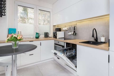 A corner of the kitchen with a small round dining table, two chairs, and decorative elements like a vase and kettle.