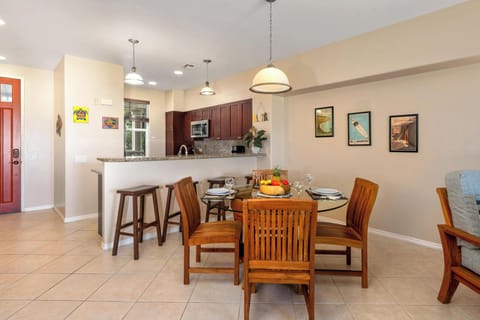 - Dining area with round glass table flows into a modern kitchen with breakfast bar   - Granite countertops, wood cabinetry, and pendant lighting add style and function   - Perfect for casual breakfasts or hosting friends for dinner