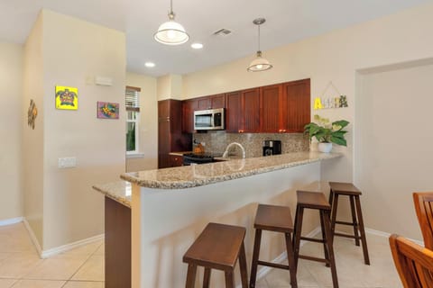 - Modern kitchen with granite counters, stainless steel appliances, and bar seating   - Four bar stools provide space for casual dining or morning coffee   - Warm wood cabinets and pendant lights create a stylish, functional space