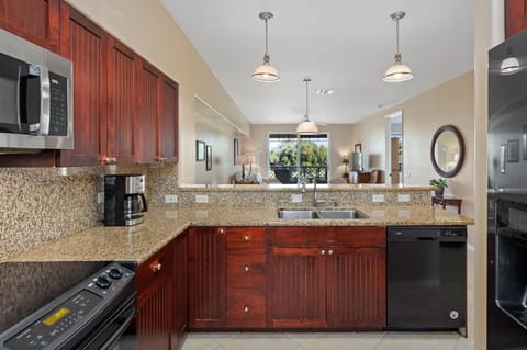 - Kitchen with granite countertops, rich wood cabinets, and modern appliances   - Double sink faces an open view to the living area for easy conversation   - Pendant lighting adds style while keeping the workspace bright