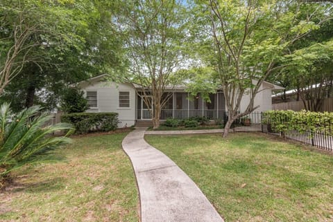 Front of home inside of fenced yard with lush landscaping.