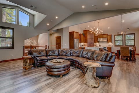 - Open concept with sectional sofa and modern lighting  
- Flows into kitchen and dining area for easy hosting  
- Cozy living area with forest views through windows
