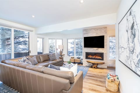 Bright and spacious living room with a large sectional, TV, and fireplace.