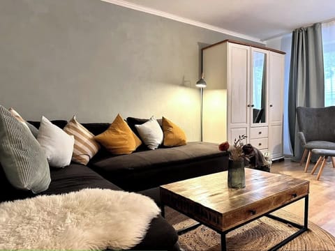 Wohnzimmer mit ausziehbarer Eckcouch. Kissen, Decken, TV.