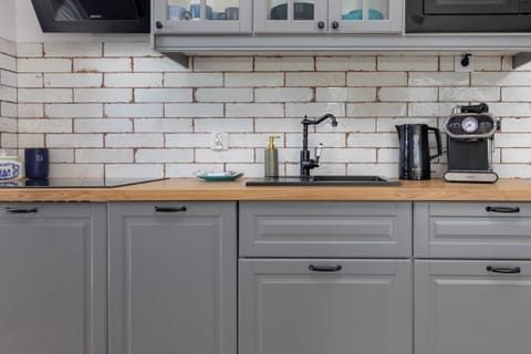 A small kitchen setup with white subway tiles, grey cabinets, and essential appliances like a coffee maker and toaster.