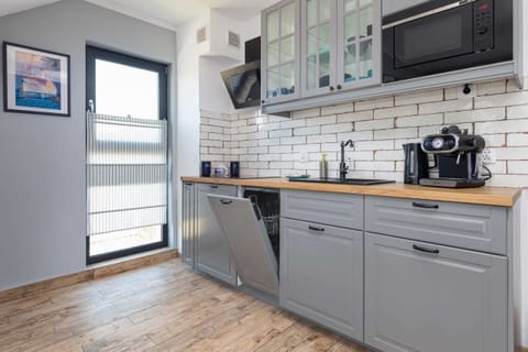 A compact kitchen equipped with basic appliances, white subway tiles, and grey cabinets for a modern look.