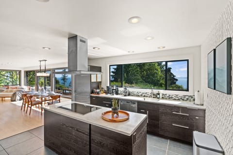 Fully stocked modern kitchen with induction stove top, double oven, coffee bar.