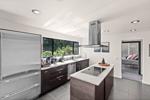 Fully stocked modern kitchen with induction stove top, double oven, coffee bar.