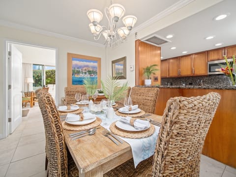 Gather for island-style dining in a beautifully set space featuring woven rattan chairs, palm centerpieces, and easy access to the full kitchen.
