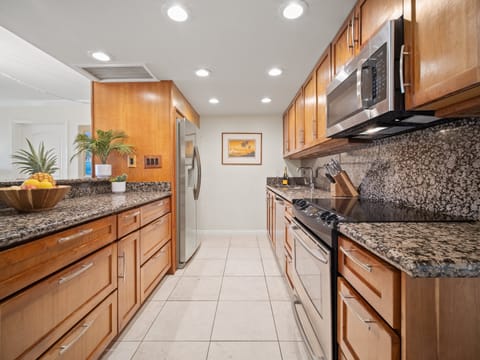 This galley-style kitchen blends modern convenience and island charm with wood cabinetry, granite countertops, and everything you need to dine in.