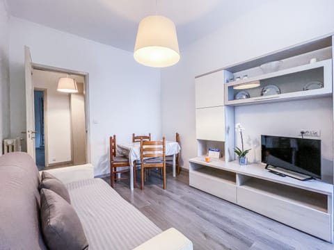 Living room with double sofa bed, flat screen TV and veranda balcony with washing machine inside.