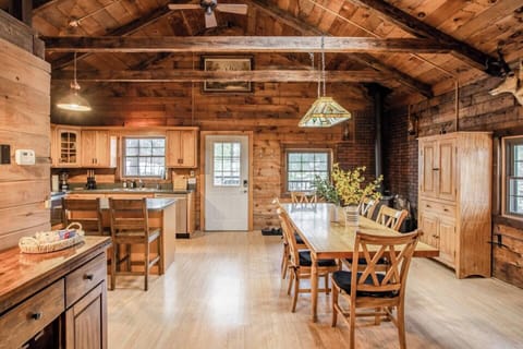 9 foot long table and vintage wood burning stove in open dining space featuring vaulted ceilings and rough sawn beams. Dining room cabinet is filled with games to keep your family busy making memories together. 