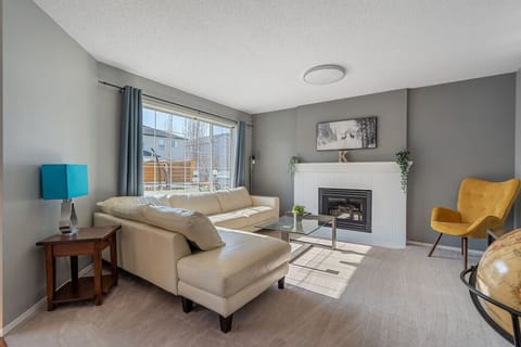 Main floor living room with a gas-lit fireplace, cozy couch and Smart TV.